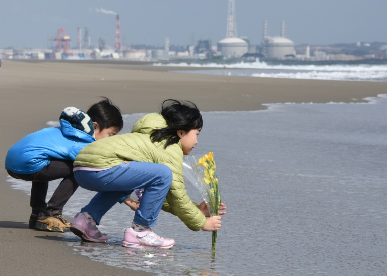 Des enfants déposent des fleurs sur la plage de Sendai, au Japon, le 11 mars 2016, en hommage au victimes du séisme et du tsunami de 2011. © AFP