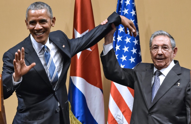 Le président cubain Raul Castro (d) lève la main du président américain Barack Obama à La Havane, le 21 mars 2016. © AFP