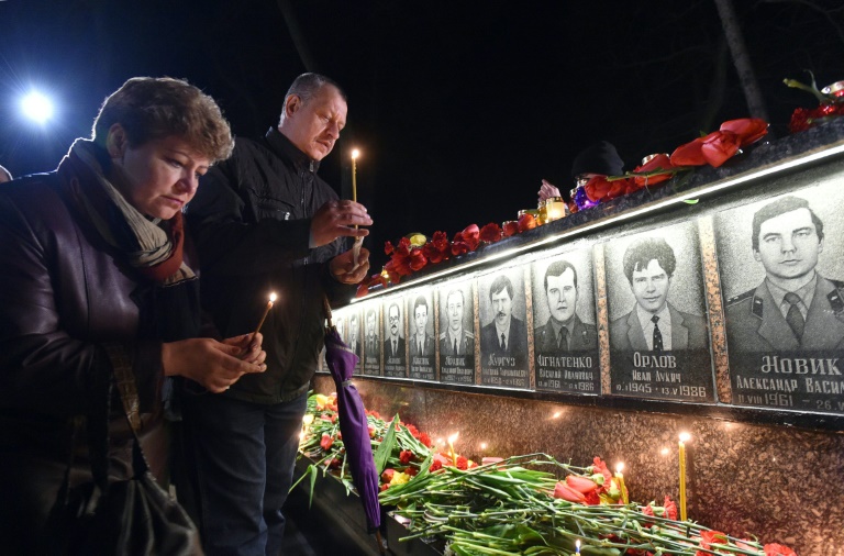 Des habitants déposent des bougies au pied du monument aux victimes de Tchernobyl à Slavoutitch, ville située à une cinquantaine de kilomètres de la centrale et construite après la catastrophe pour loger des employés du site, le 26 avril 2016. © AFP