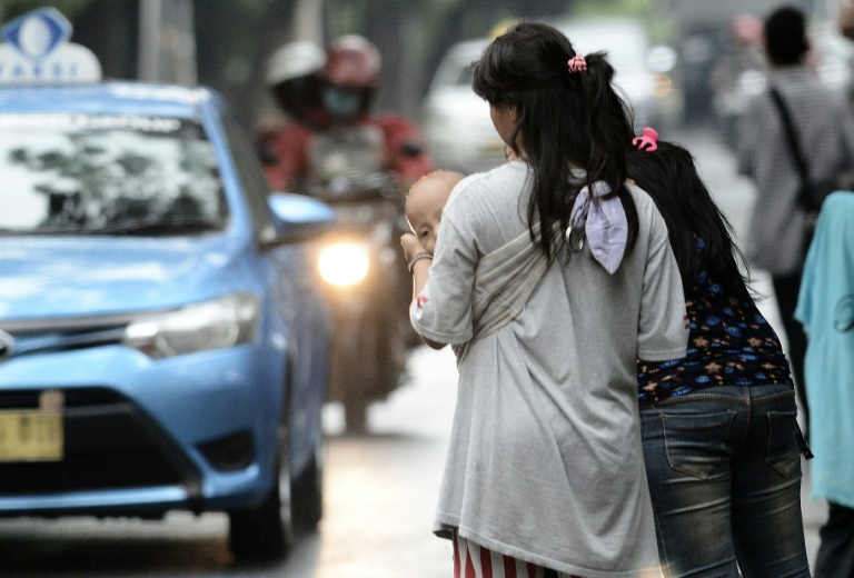 Une femme portant un enfant destiné à faire du co-voiturage à Jakarta, le 31 mars 2016. © AFP