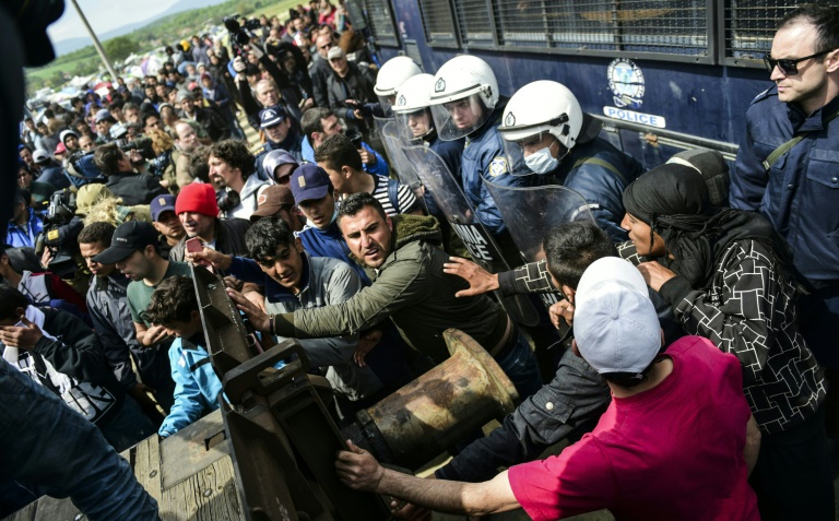 Des migrants tentent de percer une barricade installée par la police grecque à Idomeni, à la frontière avec la Macédoine, le 11 avril 2016. © AFP